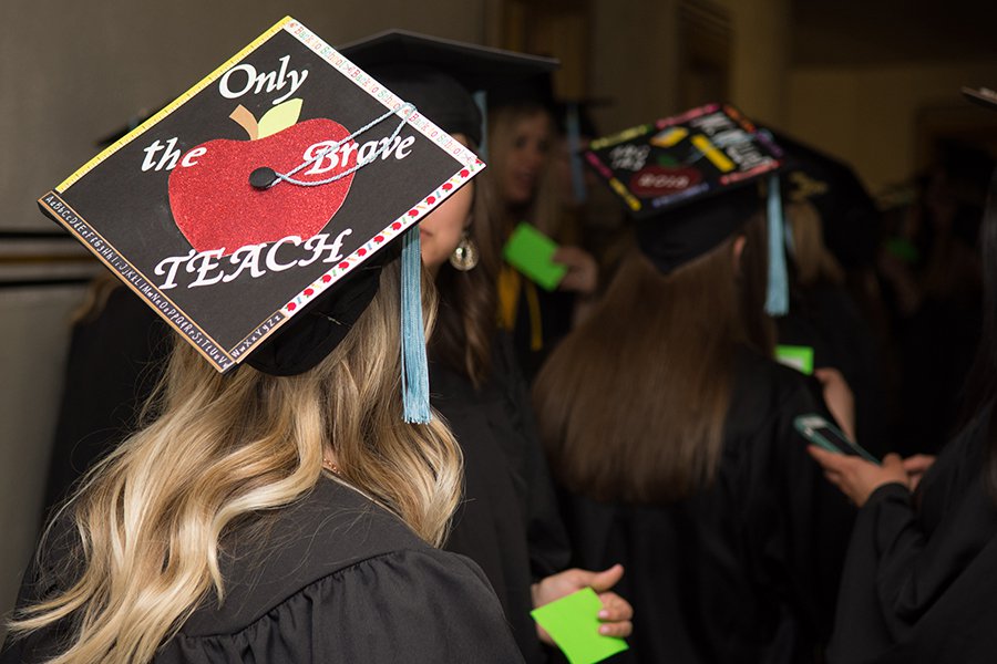 Student wearing graduation hat that reads "Only the brave teach"