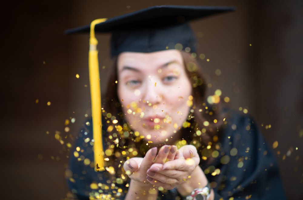 Graduating Student blowing gold confetti