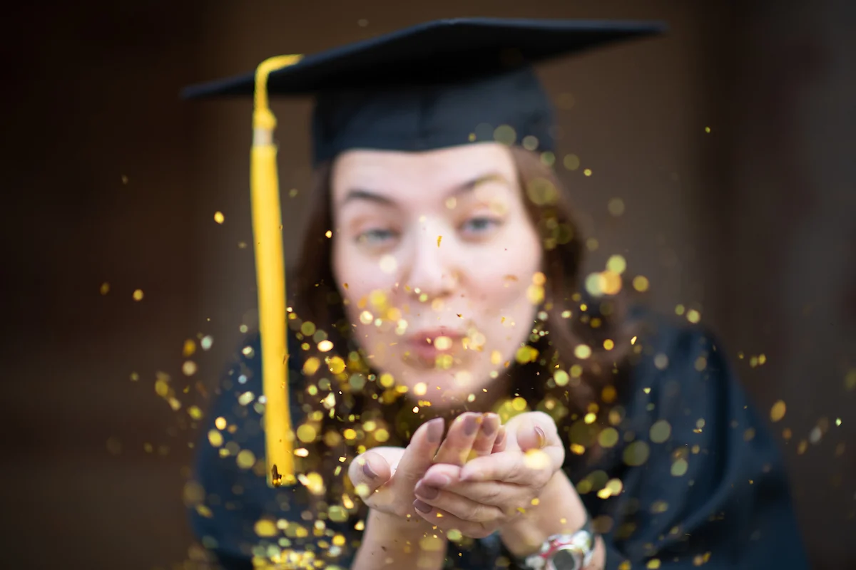 Graduating Student blowing gold confetti