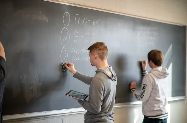 Emporia State University student solving math problem on chalkboard