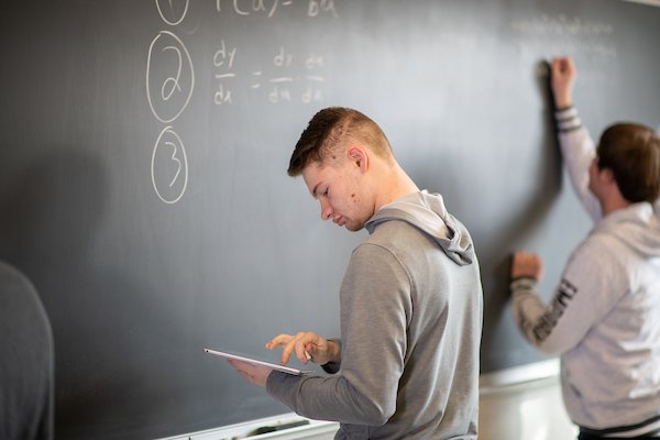 Math students working out formulas on chalkboard