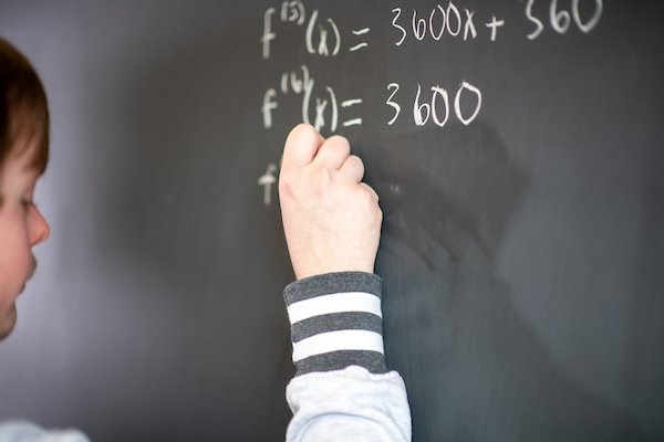 Student working out formula on chalkboard