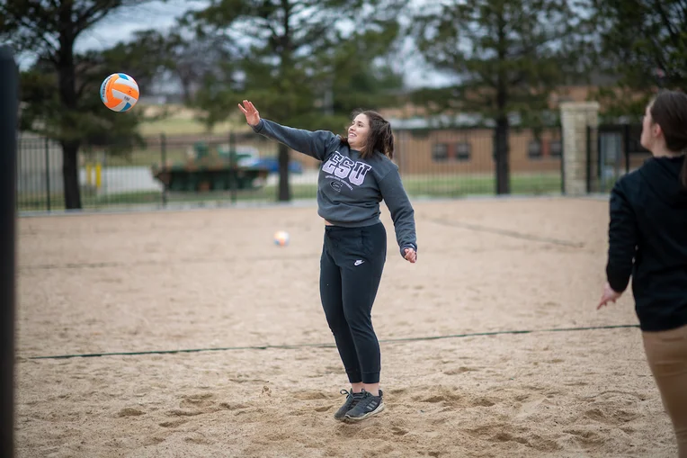 Student playing volleyball on new court on Emporia State campus
