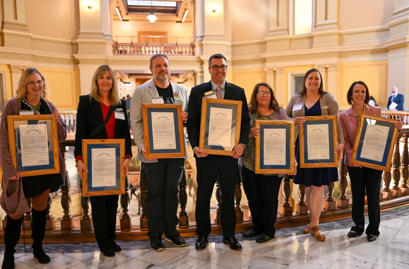 2023 Kansas Master Teachers stands in the Kansas State Capitol rotunda holding their framed certificates