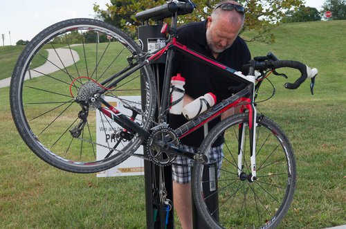 Mike Wise, director of recreation services, uses a new bicycle repair station to air a tire. The stations can suspend a bicycle and riders can use tools attached to the station to make repairs. 