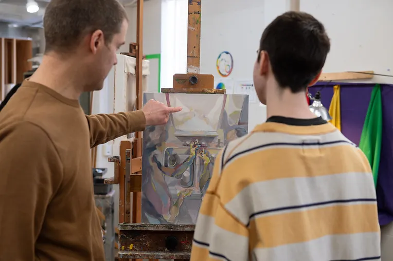 Teacher working with student on painting