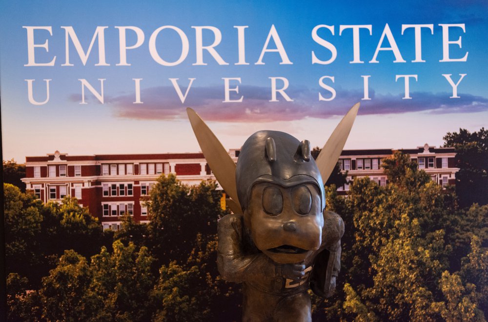 Bronze statue of Corky, Emporia State's mascot, in front of backdrop