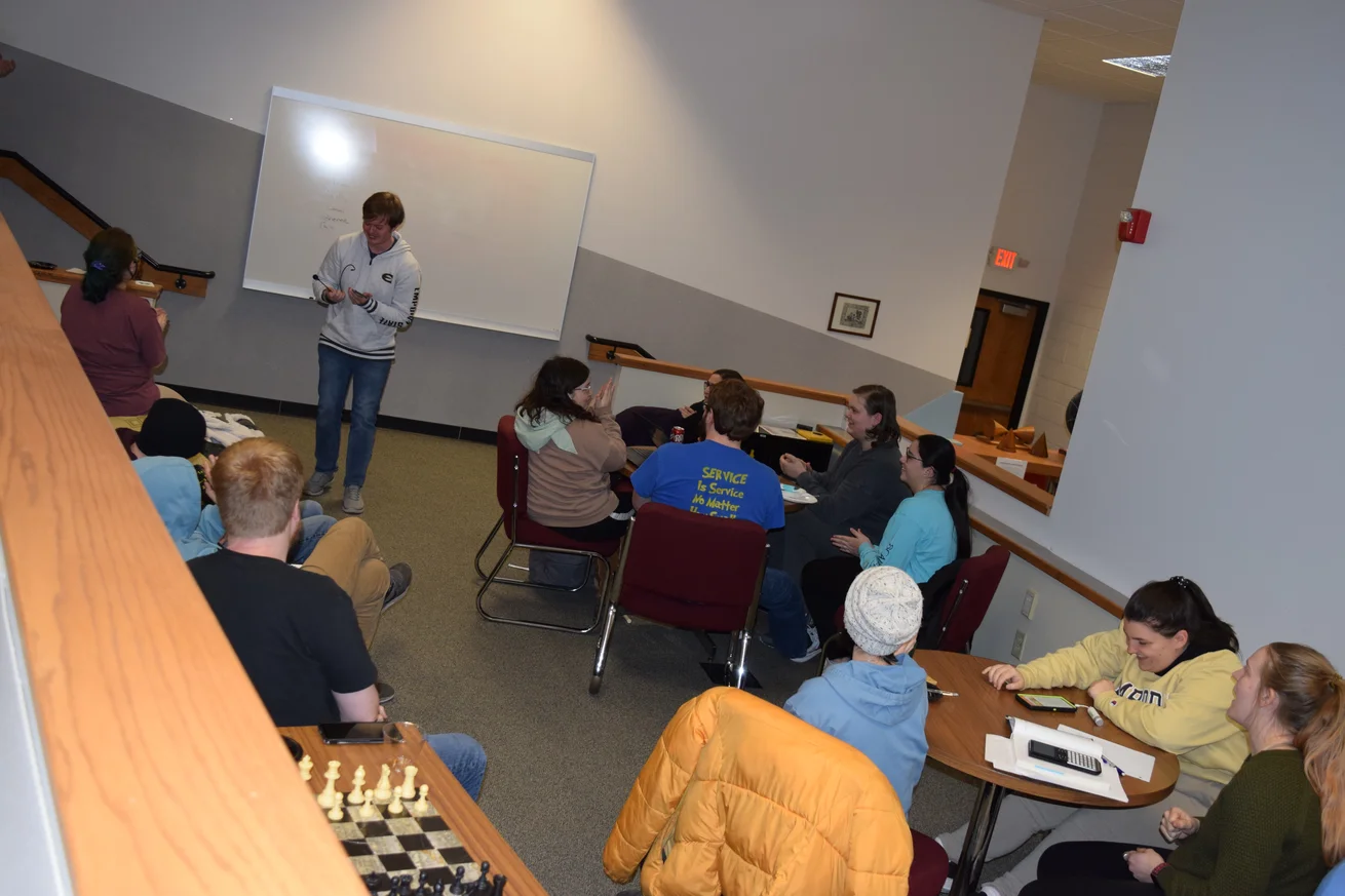 Students sitting around two round tables with one student in front