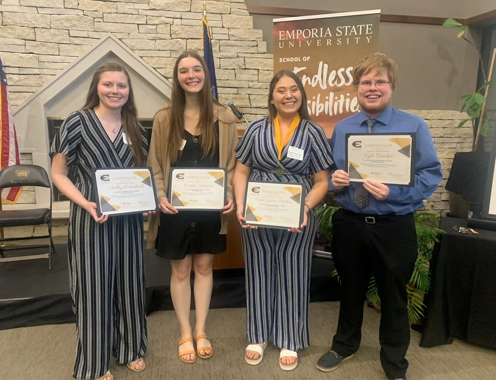 Four students are holding a certificate.