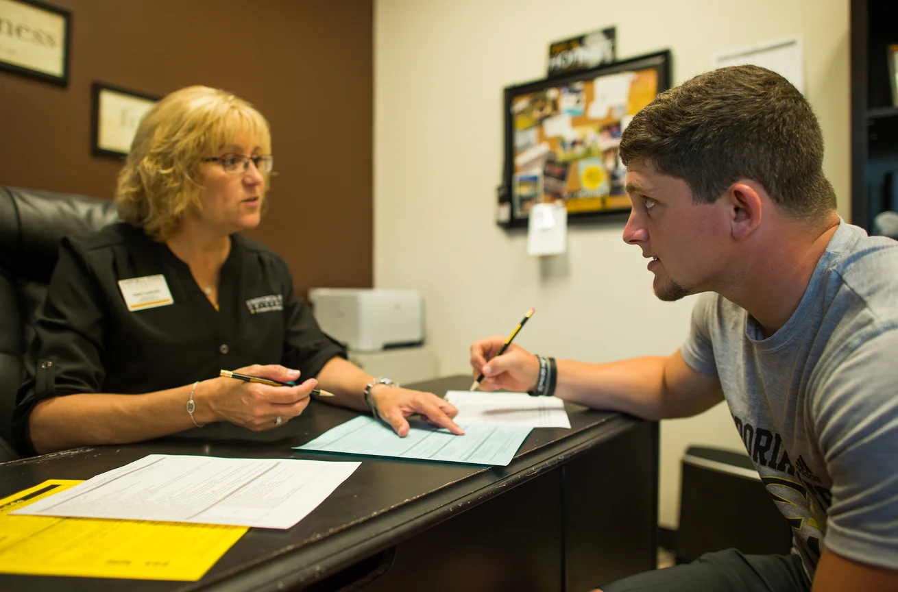 Student filling out form with Emporia State's Student Academic Center advising counselor