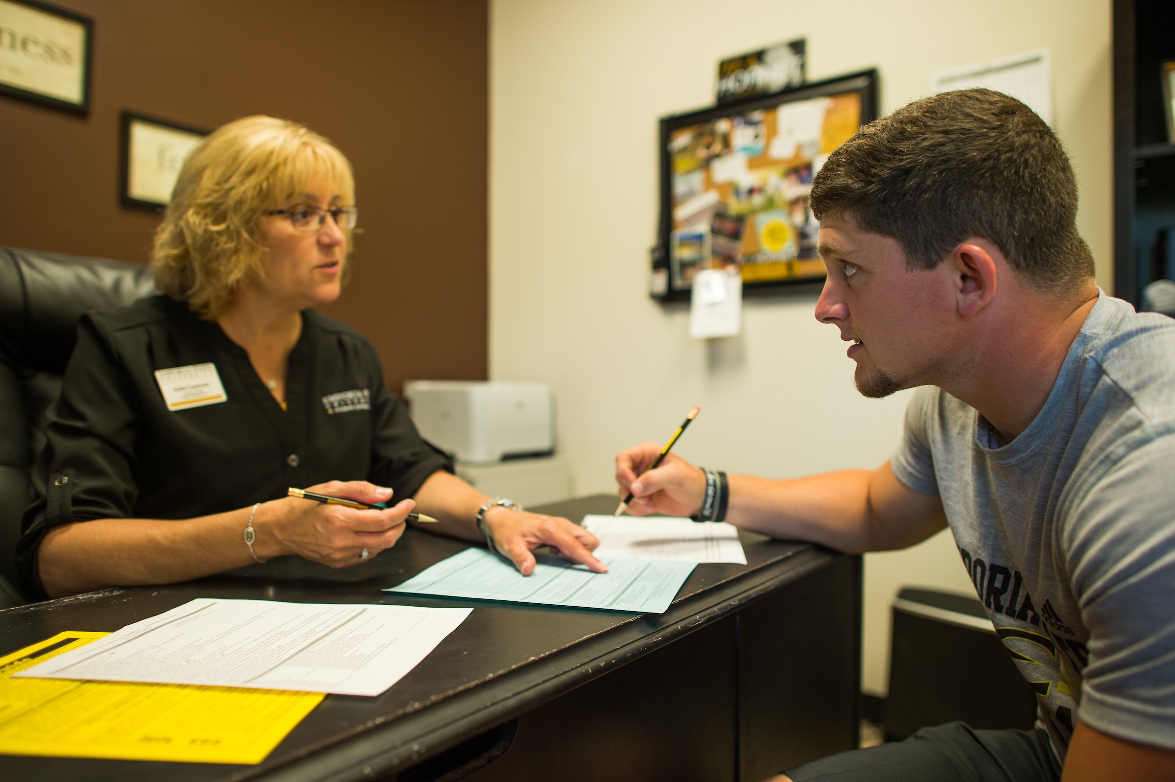 Student filling out form with Emporia State's Student Academic Center advising counselor