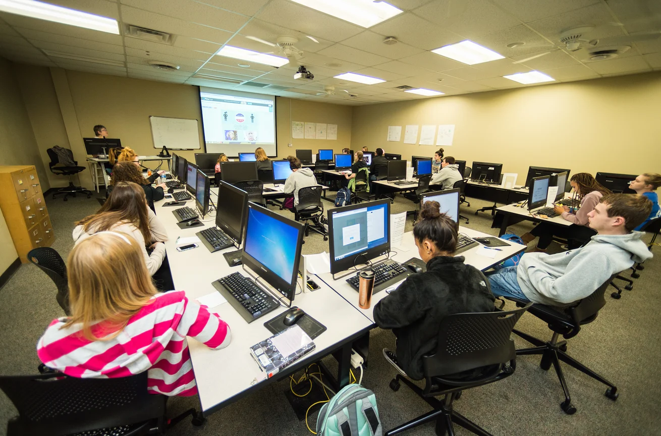 Student sitting in class with computers