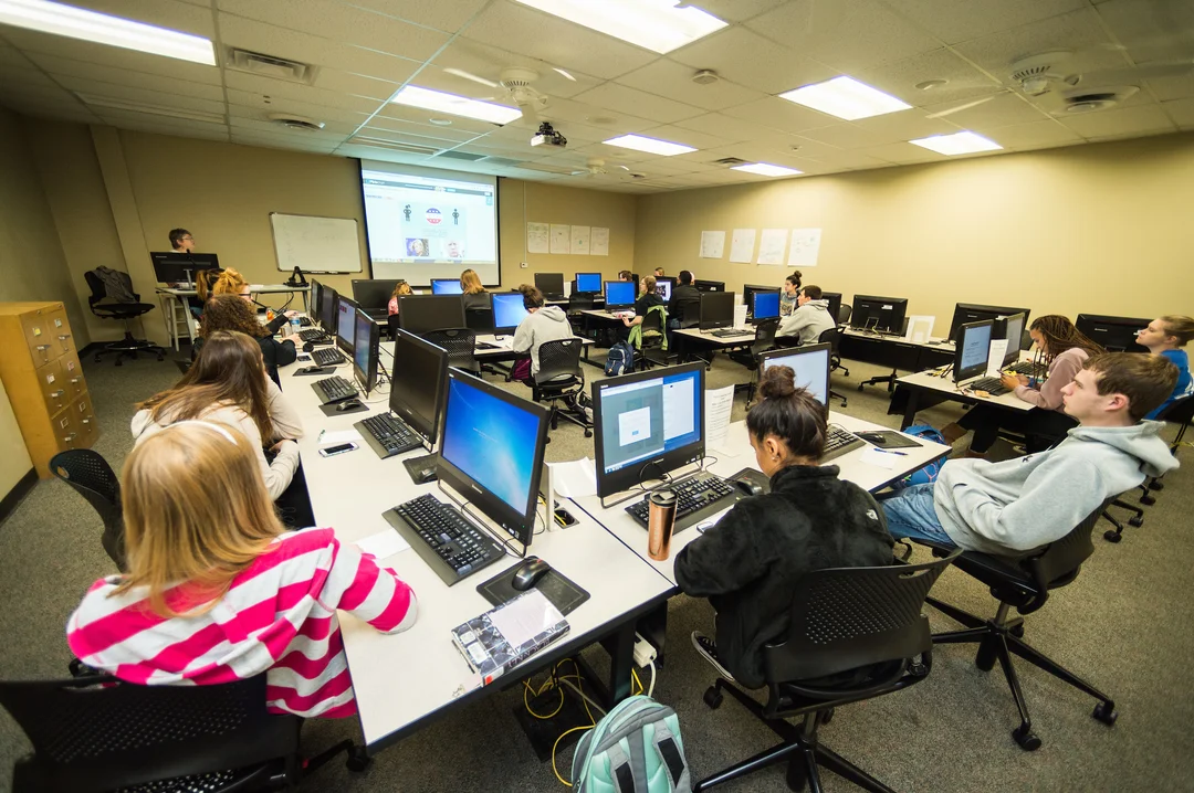 Student sitting in class with computers