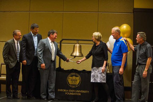 Group of people ring large bell.