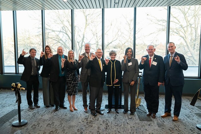 10 people standing side by side in front of wall of windows