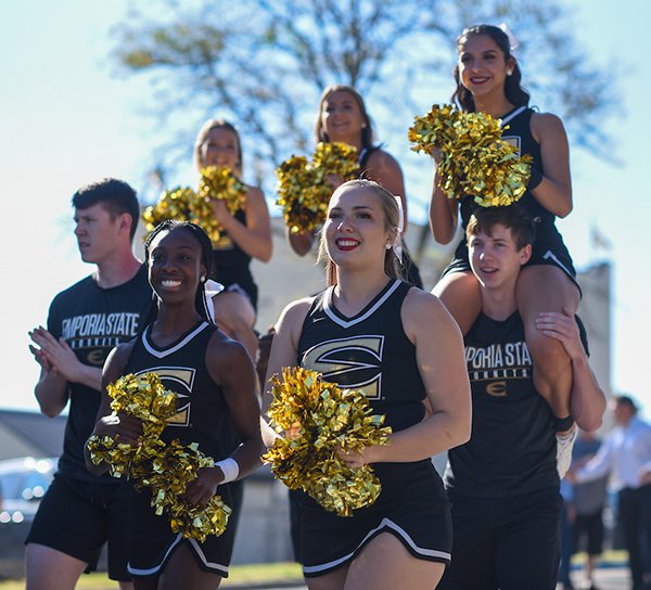 A group of cheerleaders, both men and women, walk in a parade