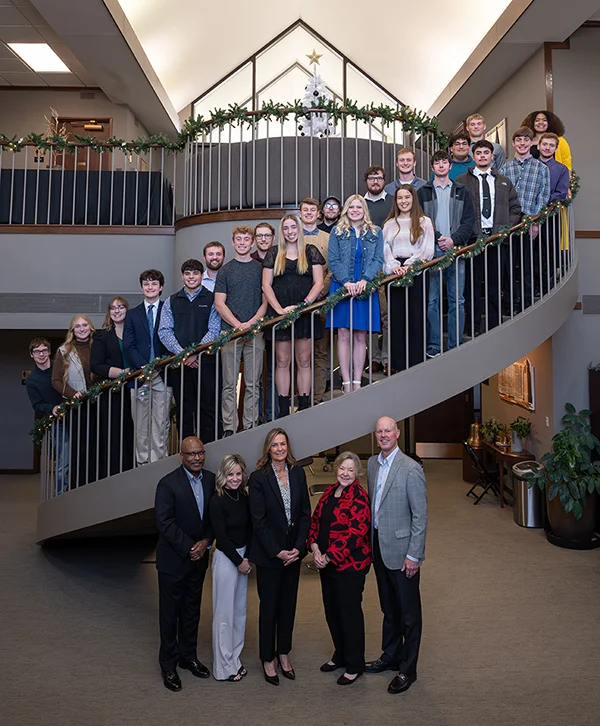 Students stand along a spiral staircase.