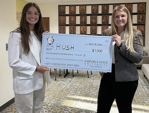 two women pose with oversized check