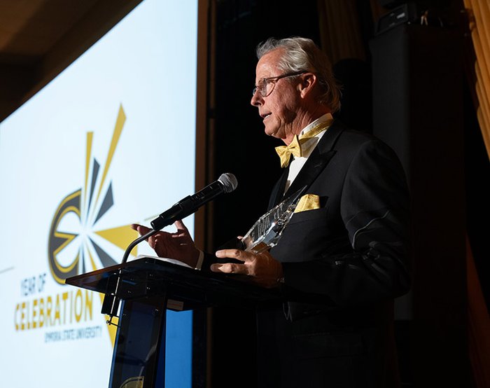 Man stands at podium holding award