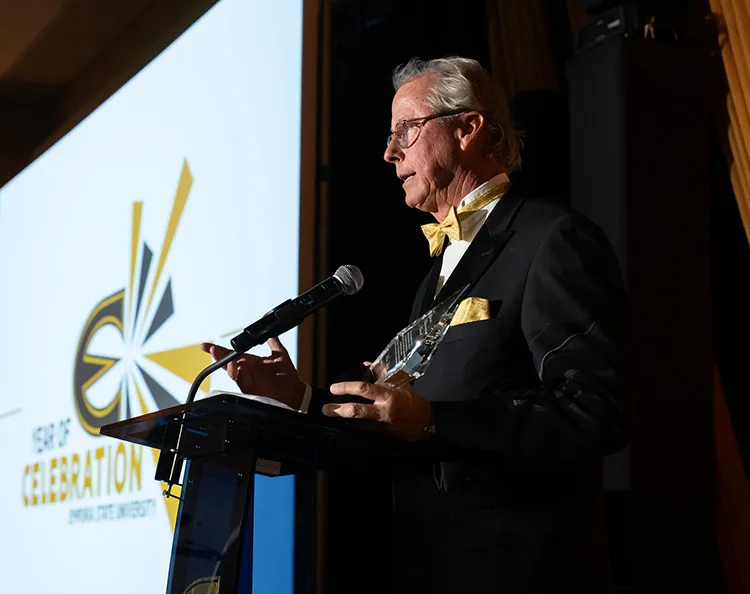 Man stands at podium holding award