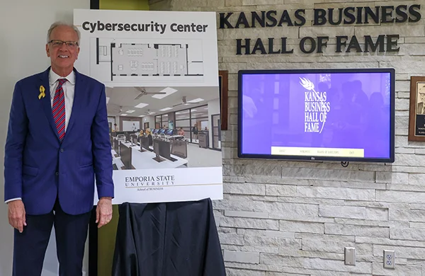 Jerry Moran next to sign board with artist drawings of classroom