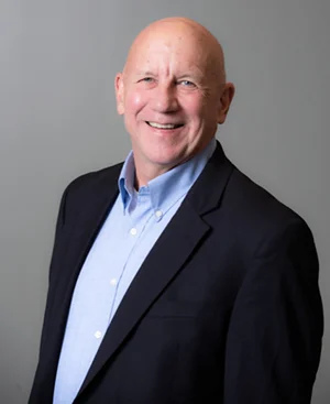 Photo of man wearing blue shirt and dark blue jacket